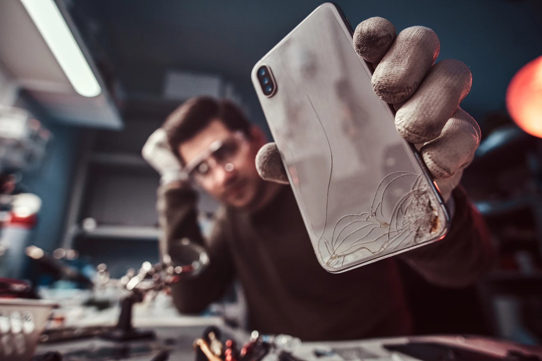 Repair technician showing a smartphone with a damaged body